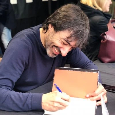 Juan del Val smiling and signing an autograph