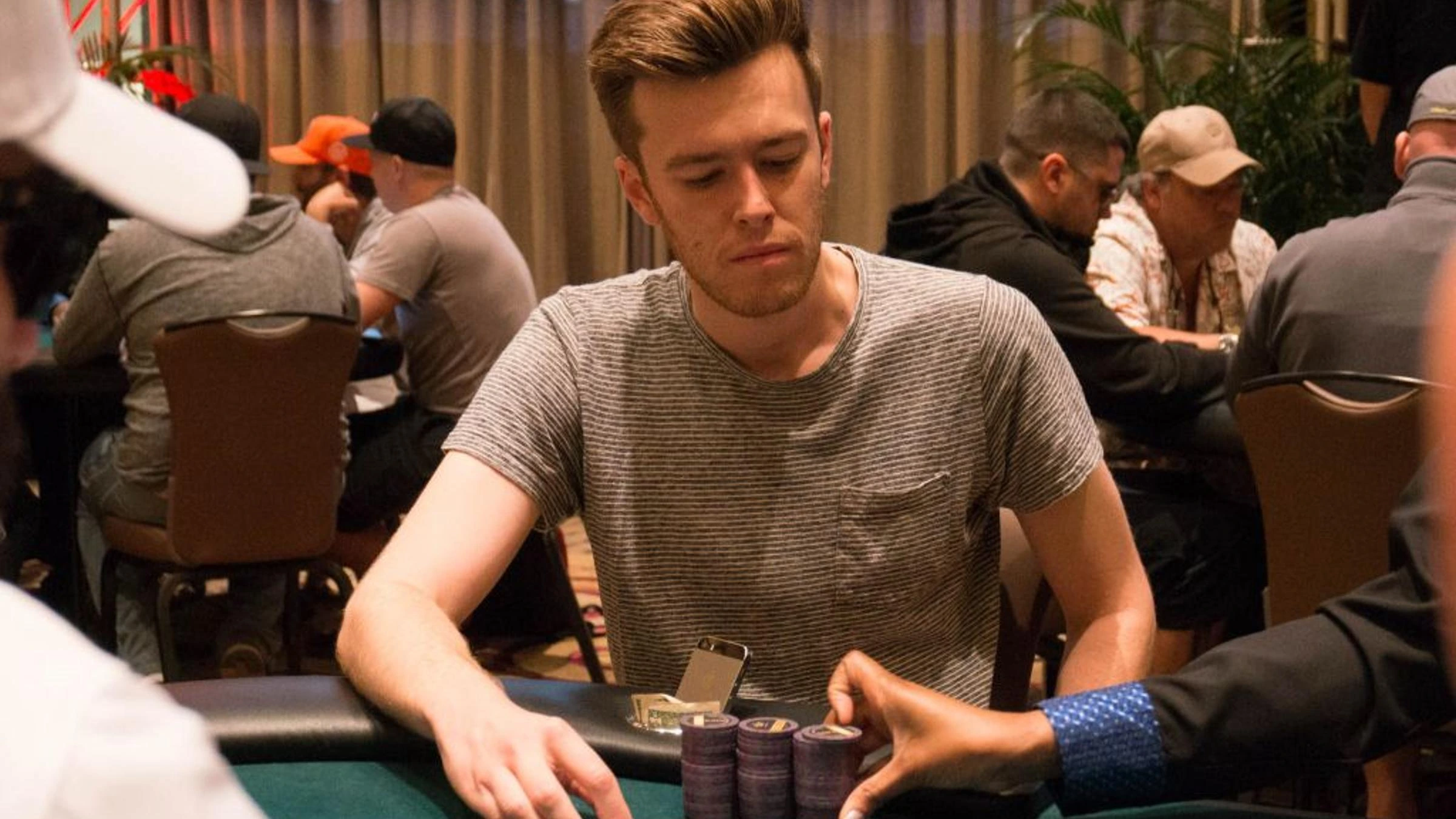 Gordon Vayo playing poker at a tournament table in a documentary-style action photo.